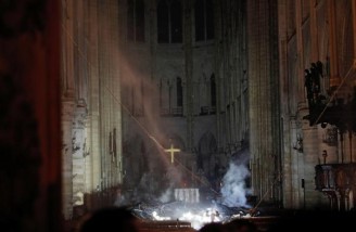 در حالیکه فروافتادن قطعات چوب سوزان از سقف به شبستان کلیسا به خطر آتش گرفتن از درون دامن می‌زند، آتش نشانان تلاش می‌کنند از گسترش حریق در درون کلیسا جلوگیری کنند| REUTERS|Philippe Wojazer|Pool